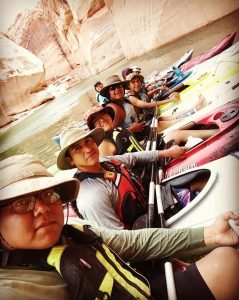 Kayakers lined up on river depicts Adventures for Hopi participants