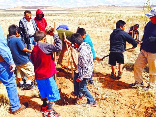 Hopi youth farming group digging holes for fruit trees.