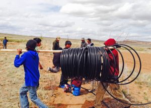 Hopi youth farming group laying out drip system pipe.