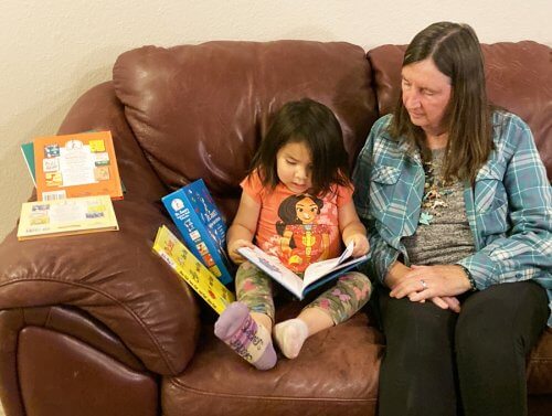 A young Hopi girl is reading a new children's book brought to her by Lainie Hoglan.