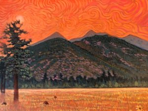 Orange hot sky of San Francisco Peaks with dried out grasslands below.