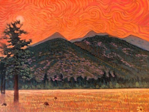 Orange hot sky of San Francisco Peaks with dried out grasslands below.